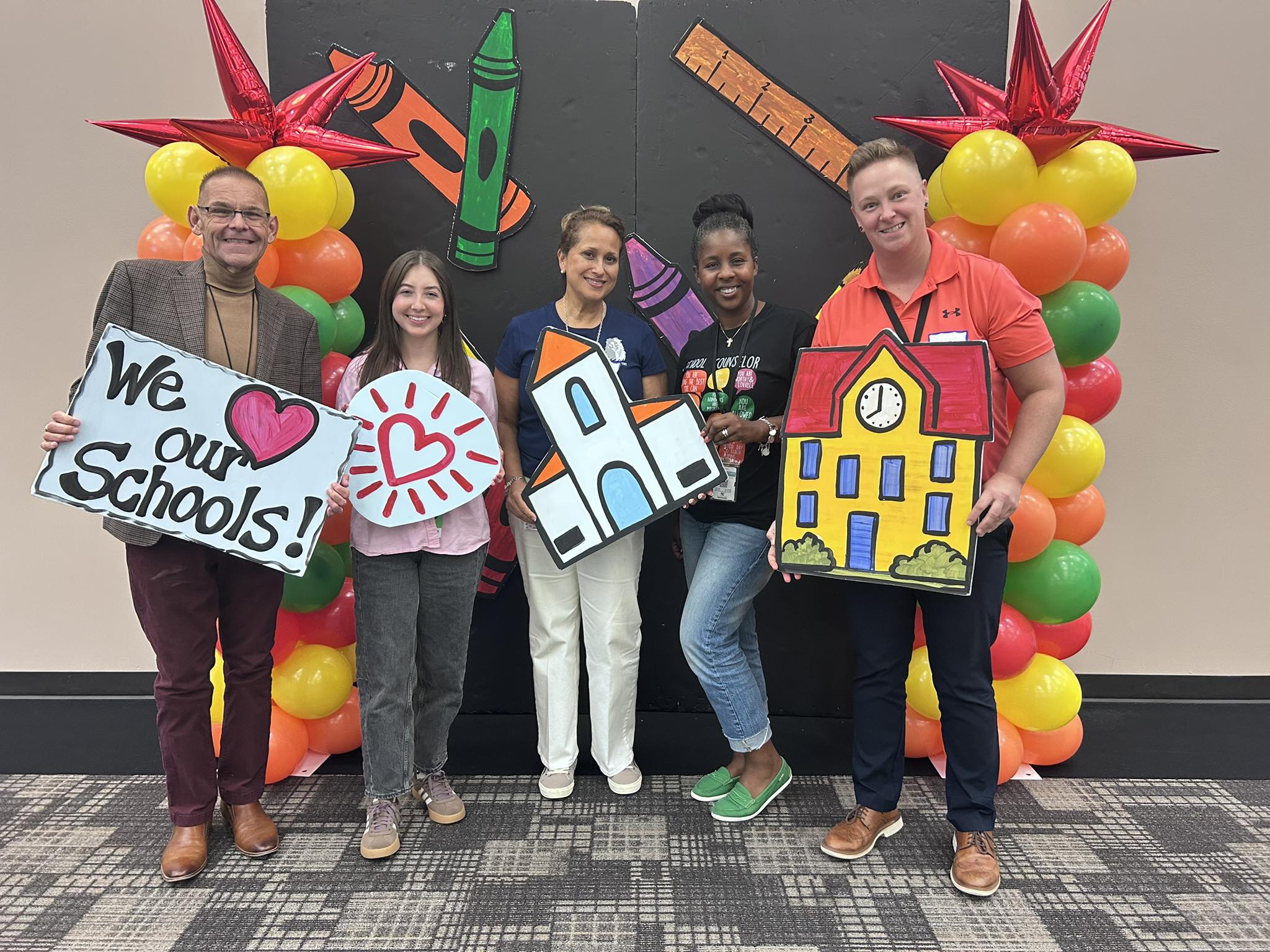 Loving Schools team holding hand-drawn signs and school illustrations
