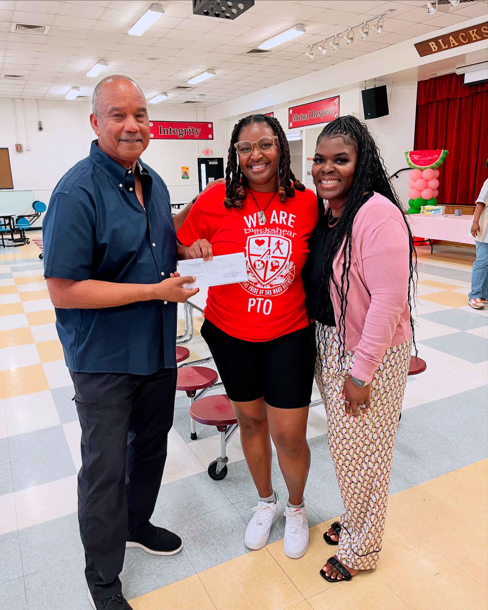 Loving Schools volunteer presenting a check to school staff